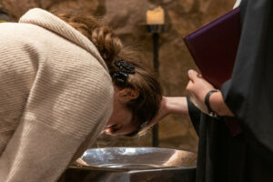 Eine Frau beugt sich für die Taufe über das Taufbecken. Symbolbild Popup-Taufe: © Rolf Oeser / fundus-medien.de
